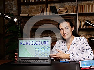 Business concept meaning FORECLOSURE with inscription on the laptop. Lender attempts to recover the amount owed on a defaulted