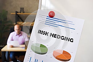 Business concept meaning RISK HEDGING with inscription on the printout with diagrams and tables. A successful businessman with