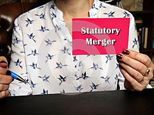 Business concept meaning Statutory Merger with inscription on pink business card