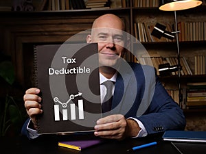 Business concept meaning Tax Deductible with sign on blank card in hand