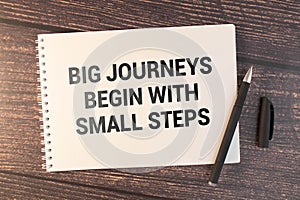 Business concept. Notebook with text Big journeys begin with small steps sheet.