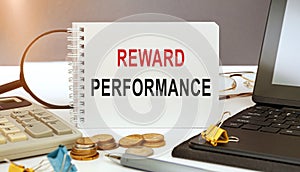 Business concept - notebook writing REWARD PERFORMANCE