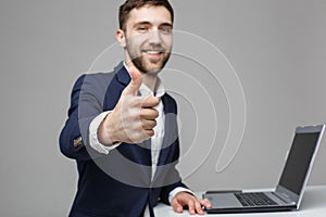 Business Concept - Portrait Handsome Business man showing thump up and smiling confident face in front of his laptop. White Backgr