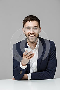 Business Concept - Portrait handsome happy handsome business man in suit playing moblie phone and smiling with laptop at work offi