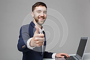 Business Concept - Portrait Handsome Business man showing thump up and smiling confident face in front of his laptop. White Backgr