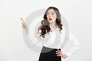 Business Concept: Portrait of surprised young businesswoman pointing finger away to copy space. Isolated on a white