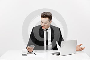 Business Concept: Portrait of young businessman using laptop computer and mobile phone holding debit card. Isolated over