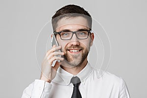 Business Concept - Portrait young handsome cheerful business man in suit talking on phone looking at camera. White background. Cop