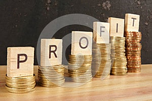 Business concept with PROFIT word on wooden plate onto hike trend stacked of coins.