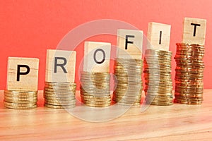 Business concept with PROFIT word on wooden plate onto hike trend stacked of coins