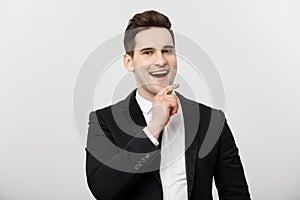Business Concept: Smiling thoughtful handsome man standing on white background and touching his chin with hand