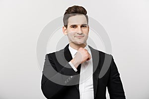 Business Concept: Smiling thoughtful handsome man standing on white isolated background and touching his chin with hand