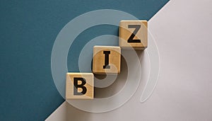 Business concept success process. Wooden block with a word `biz` stacking as step stair on paper blue and white background, copy