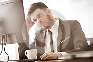 Business concept. Successful young businessman at work. Manager sitting at the office table and working on computer