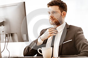 Business concept. Successful young businessman at work. Manager sitting at the office table, working on computer and