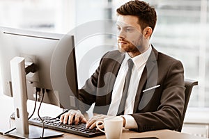 Business concept. Successful young businessman at work. Manager sitting at the office table and working on computer