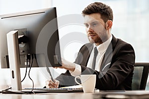 Business concept. Successful young businessman at work. Manager sitting at the office table and working on computer