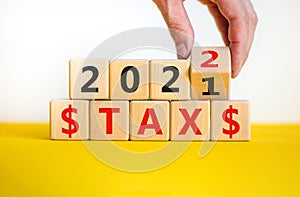 Business concept of tax planning 2022. Businessman turns wooden cube and changes words `Tax 2021` to `Tax 2022`. Beautiful whi