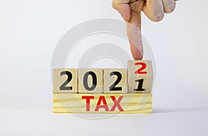 Business concept of tax planning 2022. Businessman turns wooden cube and changes words `Tax 2021` to `Tax 2022`. Beautiful whi