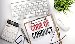 Business concept.Text CODE OF CONDUCT on paper clipboard with,pencil,glasses, keyboard and calculator on white background