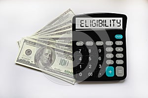 Business concept. The text Eligibility is written on a calculator on a white background next to dollars photo