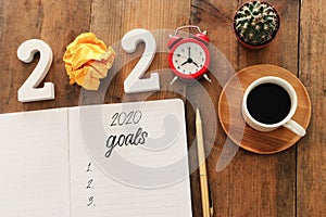 Business concept of top view 2020 goals list with notebook, cup of coffee over wooden desk