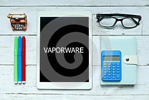 Business concept. Top view of colorful pen, calculator,glasses,pen,notebook and tablet written with Vaporware on white wooden.