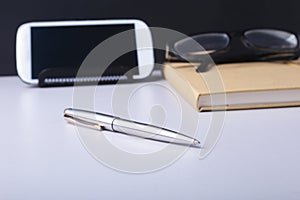 Business concept. Top view of kraft spiral notebook, glasses, smartphone and black pen on background for mockup