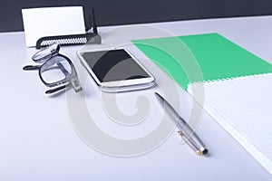 Business concept. Top view of kraft spiral notebook, glasses, smartphone and black pen isolated on background for mockup.