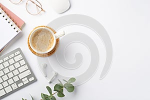 Business concept. Top view photo of workplace cup of coffee on rattan placemat wireless earbuds keyboard computer mouse copybooks