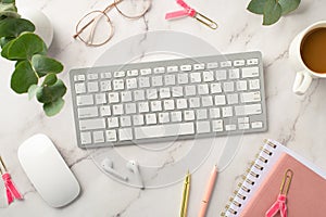 Business concept. Top view photo of workspace keyboard cup of coffee pink notepads pens computer mouse wireless earbuds glasses