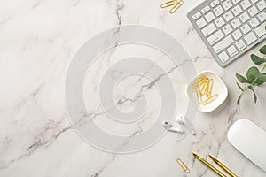 Business concept. Top view photo of workstation keyboard computer mouse wireless earbuds gold pens clips and eucalyptus on white