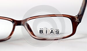 Business concept with white cube arranged in the word  â€™BIAS` and glasses.