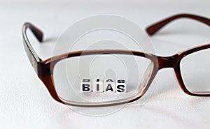 Business concept with white cube arranged in the word  â€™BIAS` and glasses.