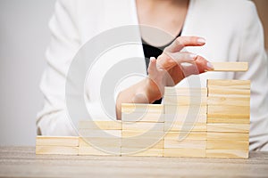 Business concept, woman`s hands make up wooden cubes symbolizing the success of the company