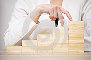 Business concept, woman`s hands make up wooden cubes symbolizing the success of the company