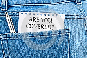 Business concept. ARE YOU COVERED text written on a piece of paper that appeared from the pocket of jeans