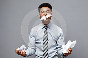 Business Concept - Young angry African American businessman while eating balled report paper. Unsuccessful Project.