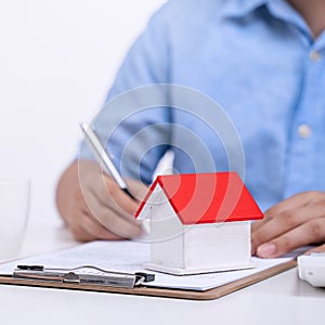 Business concept - Young Asian man in blue shirt calculates, signs agreement contract to buy a house loan payment, paying