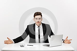 Business Concept: Young businessman working in bright office, sitting at desk, using laptop with serious facial