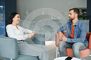 Business concept. Young dark-haired woman sitting in front of mature cheerful office manager on job interview, having