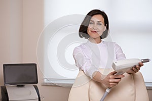 Business Concepts. Professional Confident Female Doctor Posing in Doctor`s Smock And Holding Intence Pulse Light Apparatus in