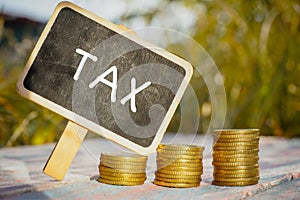 Business Conceptual. Pile of coins on the wooden table with TAX text.