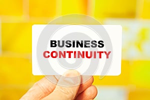 BUSINESS CONTINUITY concept on a business card in the hands of a director on a yellow background