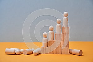 Business, corporate hierarchy. Command chain. Pyramid of wooden building blocks with small people on steps and on floor