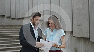 Business couple arguing outdoors. Business man throwing documents in air
