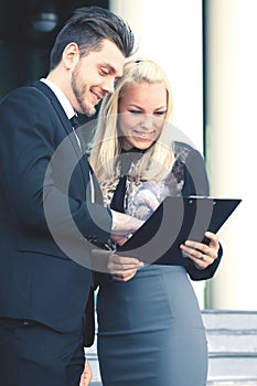 Business couple discussing document standing outside office building