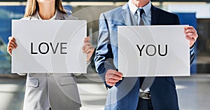 Business couple holding white placard with I love you sign