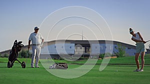 Business couple play golf on course. Two golfers practicing in country club.