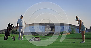 Business couple play golf on course. Two golfers practicing in country club.